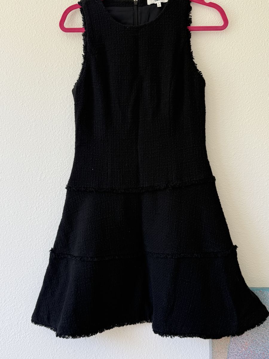 LIKELY black textured sleeveless mini dress with subtle frayed trim detail.